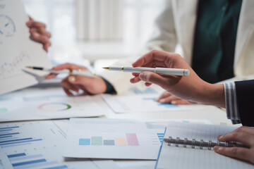 Business people analyzing financial charts and graphs using pen during corporate meeting