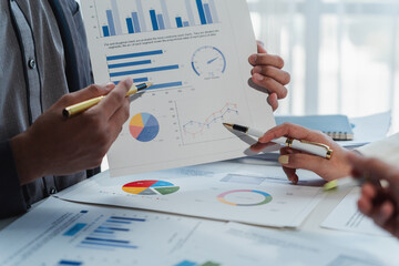 Business people analyzing financial charts and graphs using pens during a corporate meeting