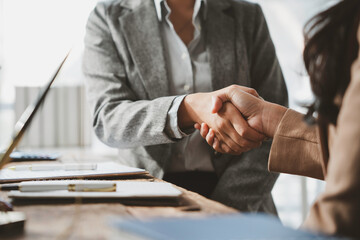 Businesswomen shaking hands after signing contract at office desk