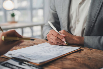 Businessman signing contract after reading terms and conditions during meeting