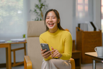 Asian businesswoman using smartphone and smiling in modern office