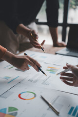 Business people analyzing financial charts and graphs using pens during a meeting