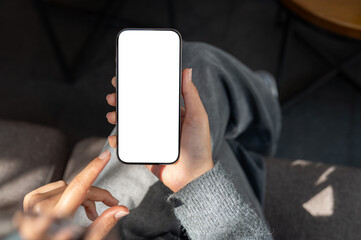 Top view of a woman sitting indoors, sunlight streaming over her as she uses her smartphone.