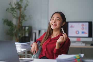 Young businesswoman smiling and holding a pen in her modern office