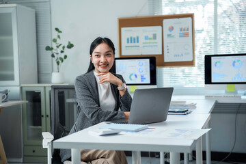 Asian businesswoman smiling and working using laptop computer in modern office