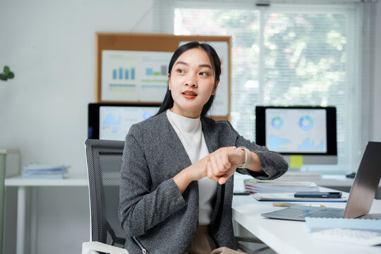 Businesswoman checking time on smartwatch in office looking away