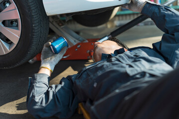 車両の下でメンテナンス作業をする40代男性整備士