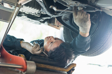 車両の下でメンテナンス作業をする40代男性整備士