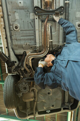 自動車点検をしながら電話で話す40代男性整備士