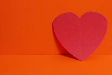Minimalist red heart shape on a bright orange background for Valentine's Day.