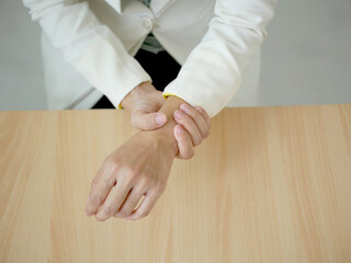 A woman's hand has a sore wrist from using a laptop for a long time. Sitting and massaging her...