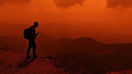 Hiker uses phone, mountaintop sunset, hazy landscape, navigation