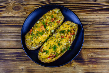Plate with baked stuffed eggplants on a wooden table. Top view