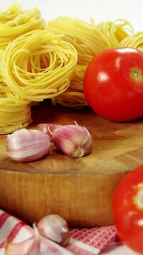 Tomatoes and raw pasta on chopping board