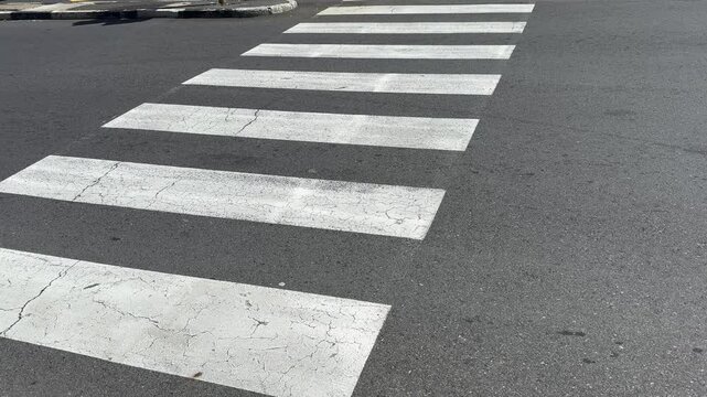 The painted lines on the street showing a pedestrian crossing .