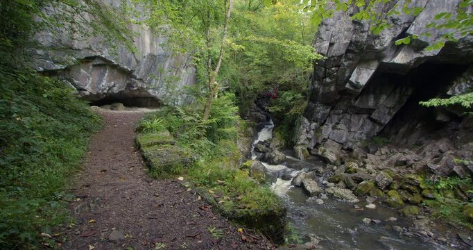 Panning shot of the river sychryd with small cave and rocky overhang at Coed-Y-Rhaidyr, Pontneddfechan, Neath,