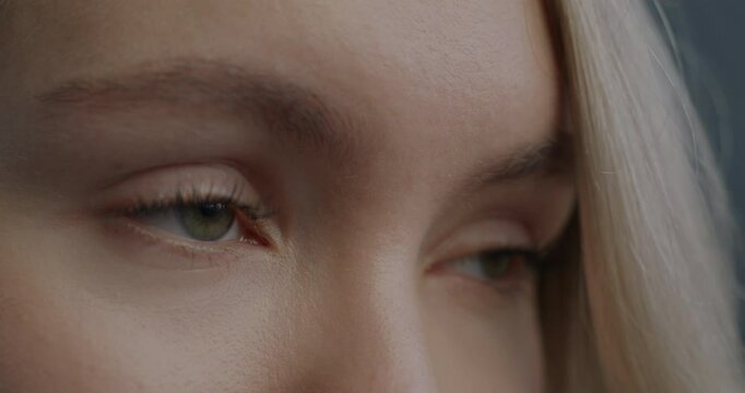 Close-up slow motion portrait of beautiful female eyes looking aside blinking on black background. Human body part and eyesight concept.