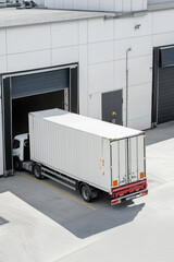 Industrial area shot of a truck loading a container onto its trailer