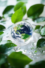 A transparent Earth surrounded by clean water droplets and green leaves, symbolizing purity and preservation