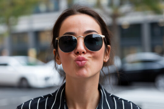 Stylish woman wearing sunglasses puckering lips