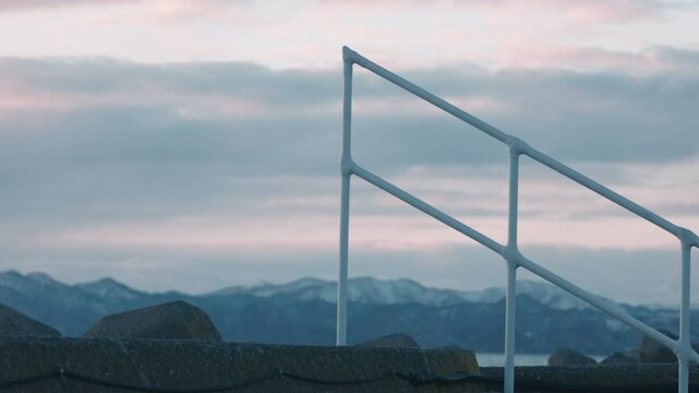 冬の防波堤にある白い階段の手すり