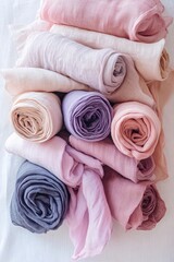 Soft pastel fabric rolls stacked on white background in a light and airy still life scene