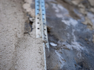 A metal bar is on the ground next to a wall