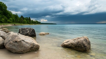 Obraz premium Serene beach scene, rocky shoreline under cloudy sky, tranquil waters inviting relaxation and reflection, perfect for nature themes.