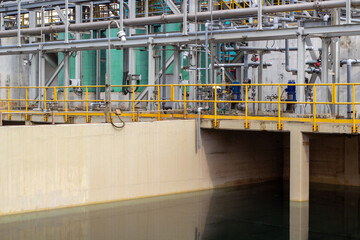 Industrial water treatment facility, pipes, metal framework, safety railings, and a water basin....