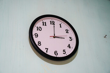 A simple analog wall clock hanging on a light-green wall. The clock shows the time. Simple Wall...