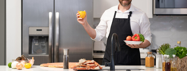 Hispanic man standing in kitchen preparing sea food. Millennial man cook tasty crab leg. Healthy...