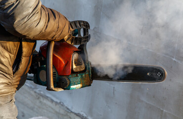 A man is holding a chainsaw with smoke coming out of it