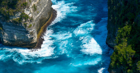 Turquoise ocean sea water white wave splashing deep blue sea. Bird eye view monster wave splash on rock. Tropical sea beach in summer seaside outdoor. Ocean island beautiful dramatic landscape.