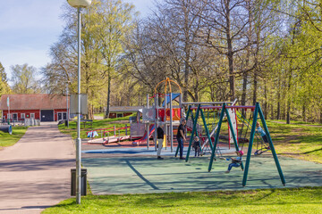 Playing children at a playground with a swing set at spring