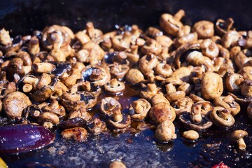 Various vegetables in a huge cauldron are cooked in oil.