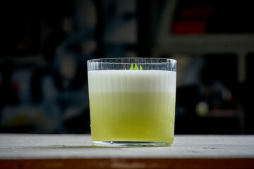 A refreshing green cocktail with a frothy top, garnished with a fresh basil leaf. The vibrant color and elegant presentation make this drink perfect for any occasion.