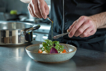 Chef Drizzling Oil Over a Gourmet Vegetable Dish