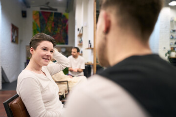 Hairdresser showing new haircut to smiling young woman in salon