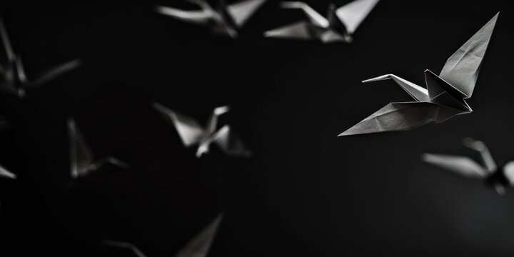 A stark black backdrop with minimalist, floating origami cranes, Delicate and balanced composition