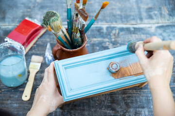 Painting a wooden furniture outdoors, an eco-friendly re-use business.