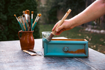 Painting a wooden furniture outdoors, an eco-friendly re-use business.