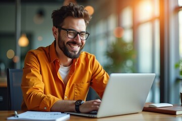 Man is smiling while using his laptop at table