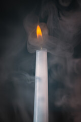 Fototapeta premium Burning candle dark background with lots of smoke around the candle 