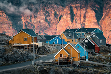 View of beautiful colorful greenlandic houses in a small picturesque village Uummannaq during sunny evening with enlightened mountain in backrgound. West Greenland. Autonomous territory of Denmark.  © Ji