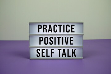 Practice Positive Self Talk text on light box on purple background