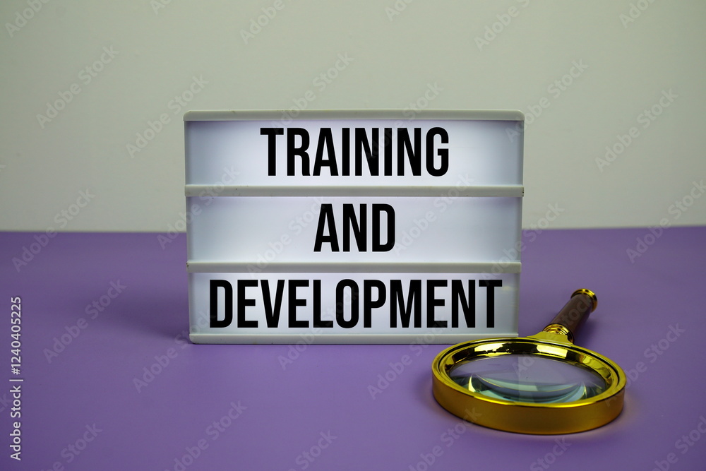 Poster training and development text on led lightbox with magnifying glass on purple background