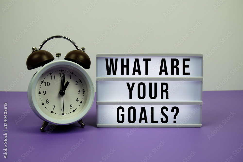 Poster what are your goals? text on light box with alarm clock on purple background