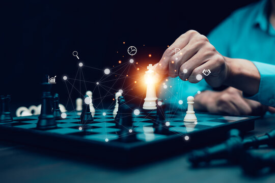 Business strategy and decision-making concept. A person moves a chess piece on chessboard with futuristic network connections, symbolizing leadership, planning, and competitive analysis in business.