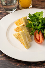 Toast with cheddar cheese and tomatoes and parsley on a white porcelain plate