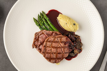 Grilled beef steak with red wine sauce, mashed potatoes, and asparagus